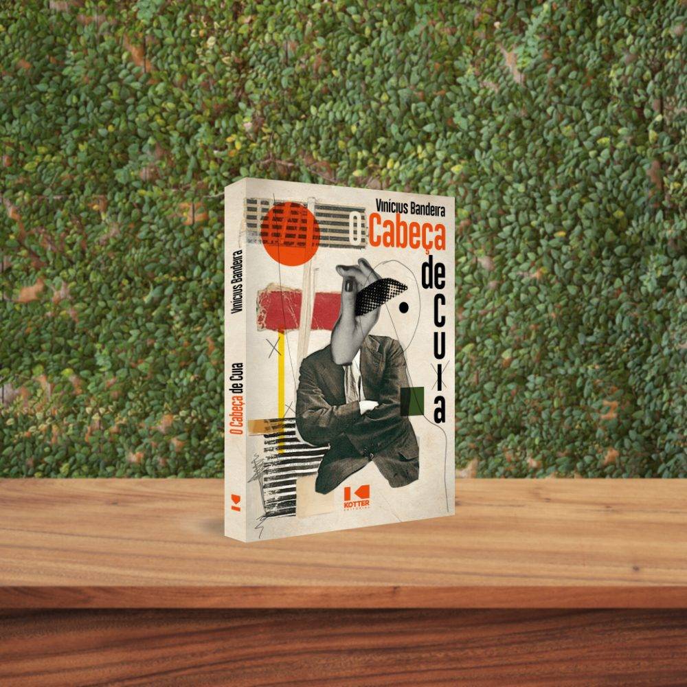 O livro O cabeça de cuia de Vinicius Bandeira em pé sobre uma mesa de madeira, ao fundo há uma cerca viva formando uma parede de plantas.