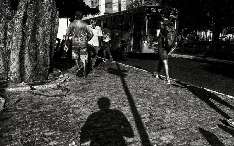 Foto em preto e branco de uma rua de Teresina com um ônibus e pessoas passando. A foto é para a exposição Ricorrenze de Vinicius Bandeira.