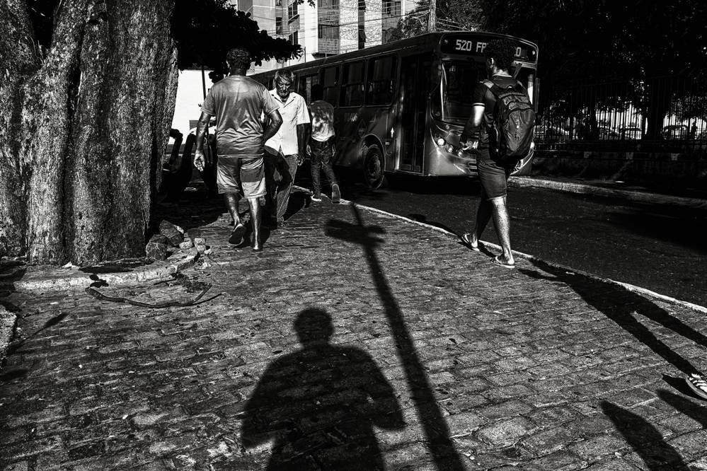Foto em preto e branco de uma rua de Teresina com um ônibus e pessoas passando. A foto é para a exposição Ricorrenze de Vinicius Bandeira.