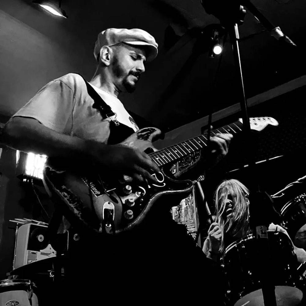 Foto de Sid Vítor em apresentação tocando guitarra. A foto está em preto e branco.