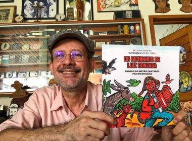 Foto de Wilson Seraine sorrindo e segurando o livro dele Os bichinhos de Luiz Gonzaga.