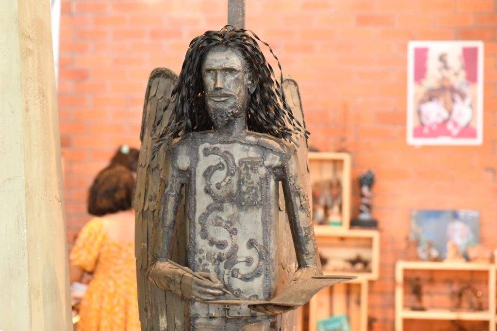 Foto do Cantinho da Geleia Total no Salipi de 2023. Em destaque uma escultura de Torquato Neto com asas de anjo torto.
